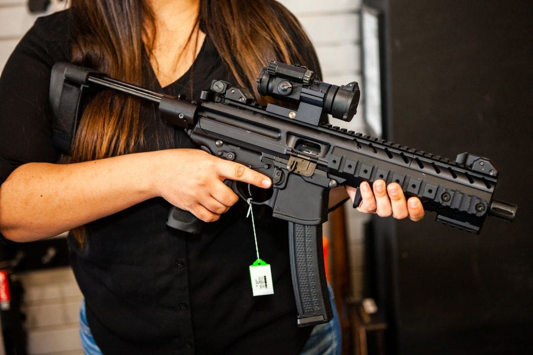 A woman holding an ar-1 5 rifle with a scope attached.