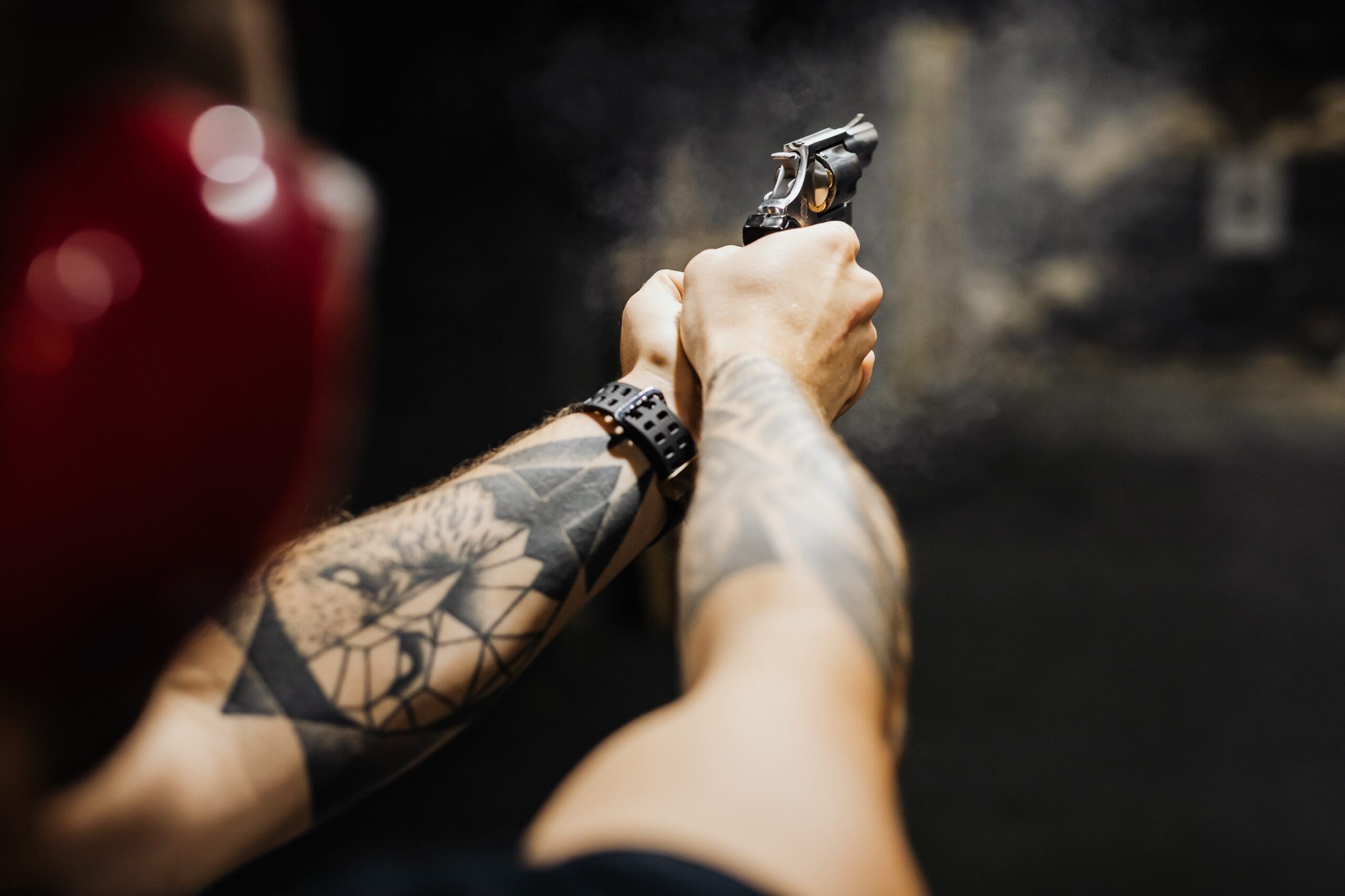 A person with tattoos holding a gun in their hands.