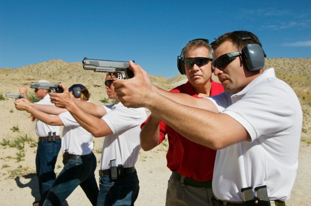 A group of men holding guns and wearing ear muffs.