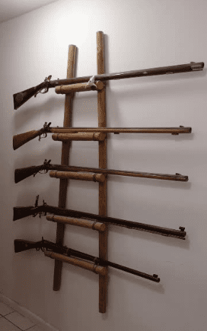 A wall mounted rack of six different guns.