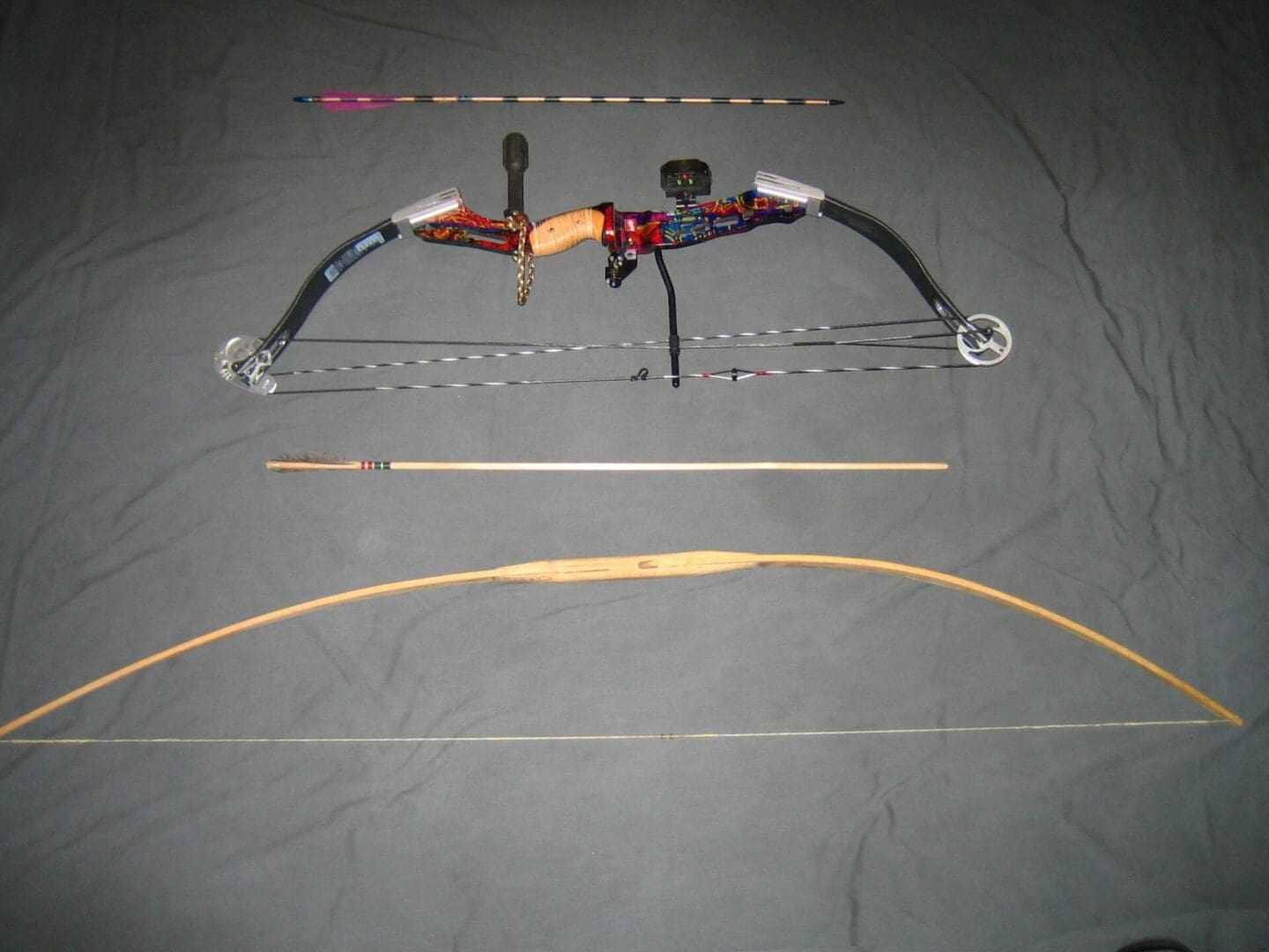 A bow and arrows are laying on the ground.